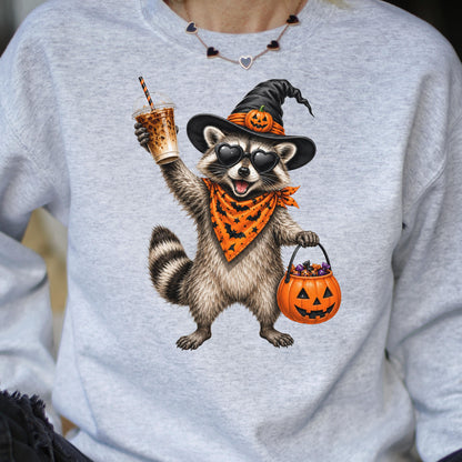 May include: A light gray sweatshirt featuring a graphic of a raccoon wearing a black witch hat with a small pumpkin, heart-shaped sunglasses, and an orange bandana with black bats. The raccoon holds an iced coffee and a pumpkin candy bucket.