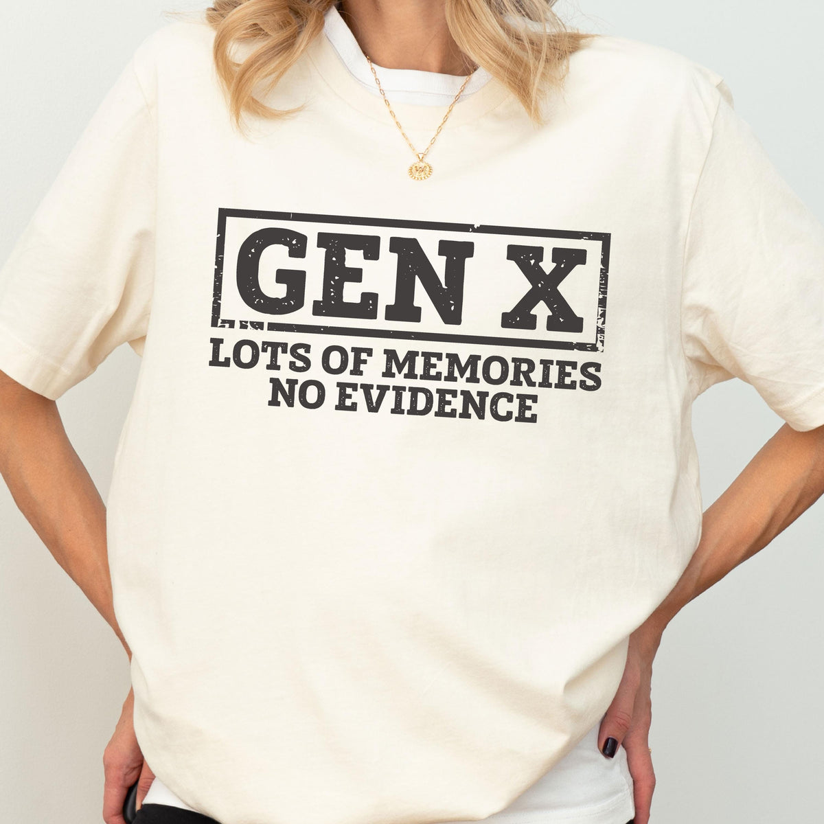 May include: A cream-colored short-sleeve t-shirt featuring a black rectangular graphic with the text "GEN X" in a bold, distressed font. Below the box, the text reads "LOTS OF MEMORIES NO EVIDENCE" in a matching black, distressed, sans-serif typeface.