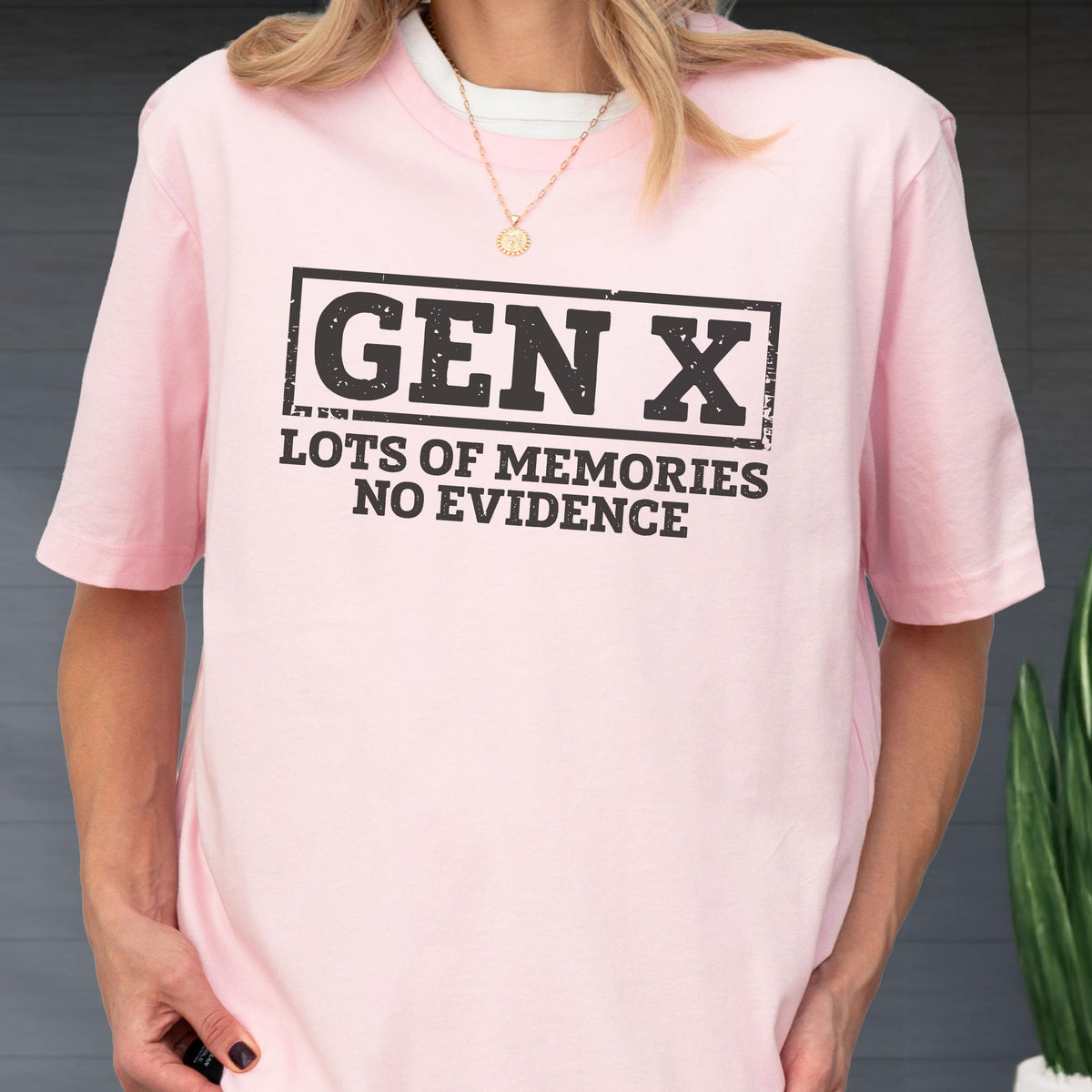 May include: A light pink short-sleeved t-shirt featuring a black rectangular graphic with the text "GEN X" in a bold, distressed font, followed by the text "LOTS OF MEMORIES NO EVIDENCE" in a smaller, matching black distressed typeface.