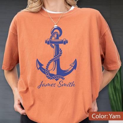 May include: A burnt orange short-sleeve t-shirt featuring a large blue graphic of a ship anchor wrapped in rope. Below the anchor, the name James Smith is printed in a blue script font. The shirt has a crew neckline and a relaxed fit.