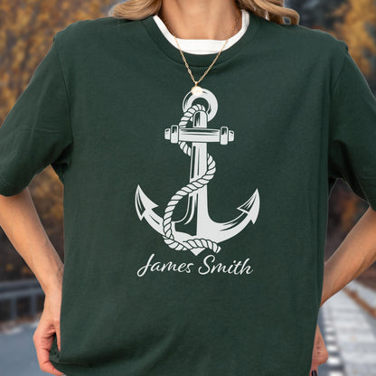 May include: A dark forest green short-sleeved t-shirt featuring a large white graphic of a nautical anchor wrapped in a rope. Below the anchor, the name James Smith is printed in a white cursive script font. The shirt has a crew neckline.
