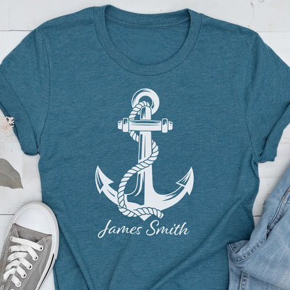 May include: A heathered teal short-sleeve t-shirt featuring a large white graphic of a nautical anchor wrapped in rope. Below the anchor, the name James Smith is printed in a white script font. The shirt has a crew neckline and a standard fit.