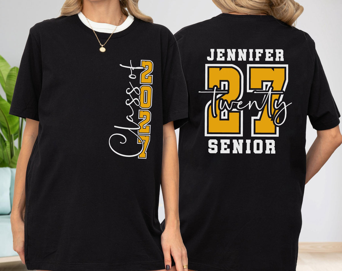 May include: A black t-shirt featuring a vertical white script and yellow block text on the front that reads Class of 2027. The back displays the name Jennifer in white, large yellow block numbers 27, the word Twenty in script, and Senior.
