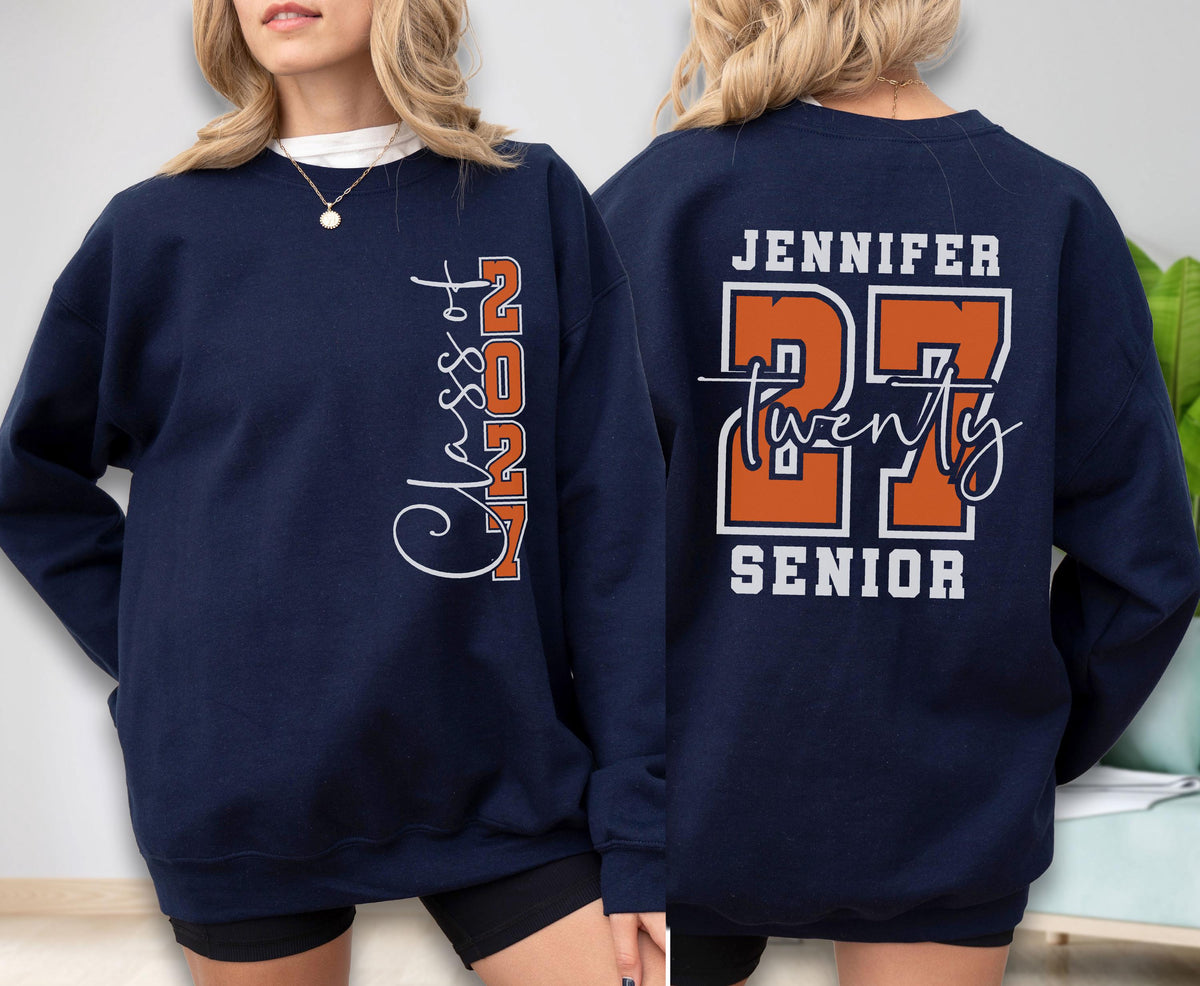 May include: A navy blue crewneck sweatshirt featuring white and orange graphics. The front displays vertical text reading Class of 2027. The back features the name Jennifer, the number 27 in large orange font, the word Twenty, and the word Senior.
