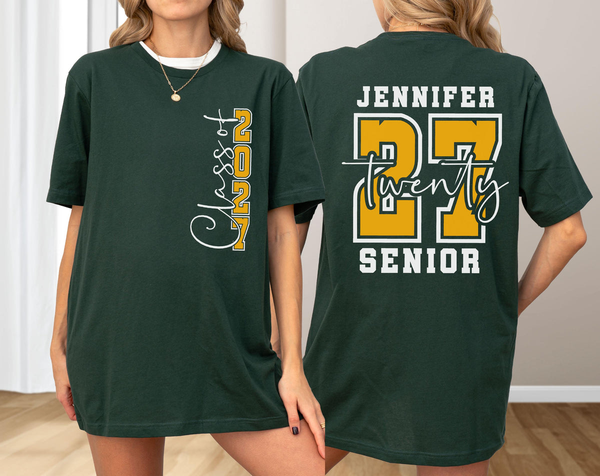 May include: A dark green short-sleeve t-shirt featuring a white and yellow graphic on the front that reads Class of 2027. The back of the shirt displays the name Jennifer, the number 27 in large yellow font, the word twenty, and the word SENIOR.
