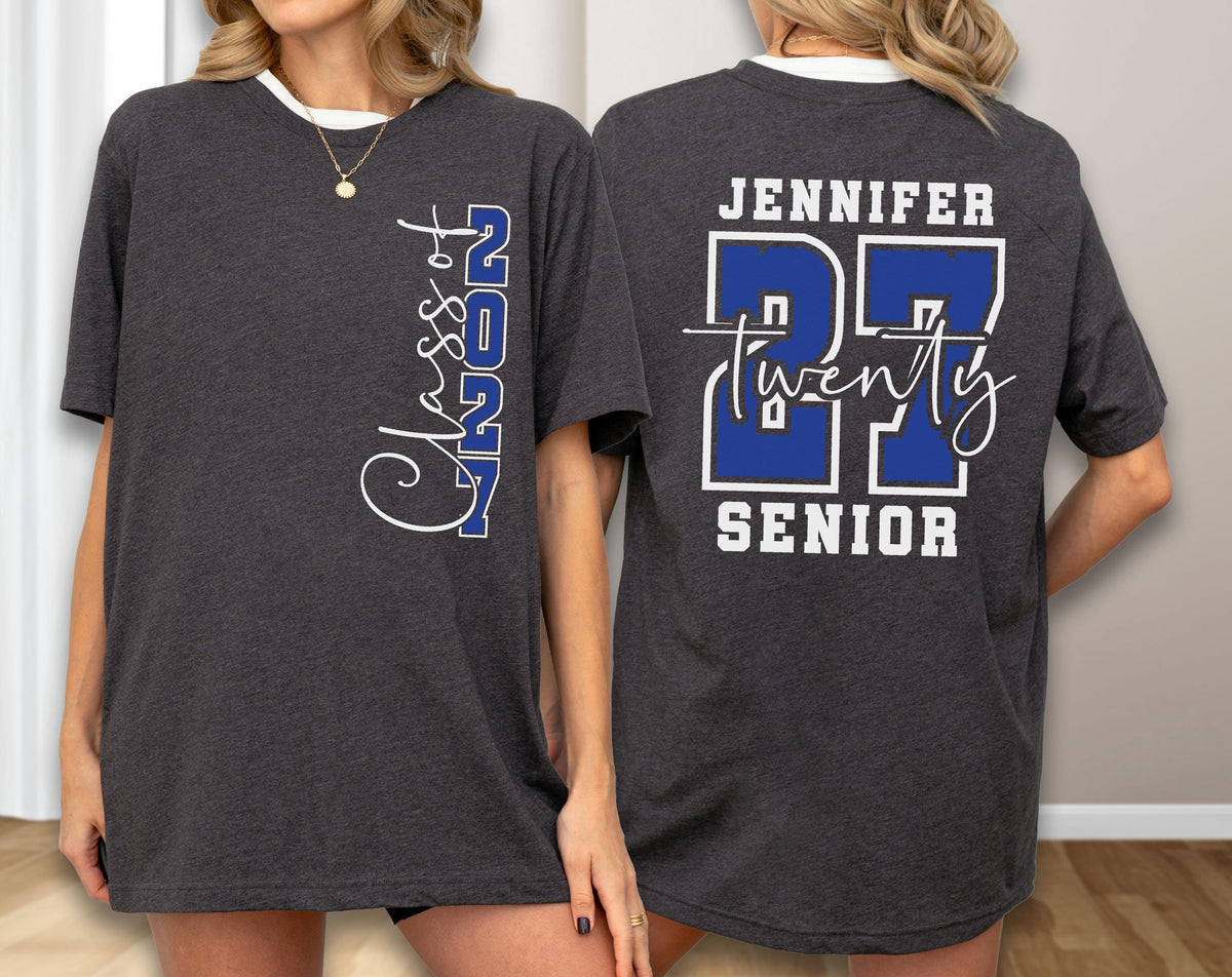 May include: A dark charcoal gray short-sleeve t-shirt. The front features the vertical white text Class of 2027 with 2027 in blue. The back displays the name Jennifer above large blue numbers 27, the word twenty in white script, and the word Senior.