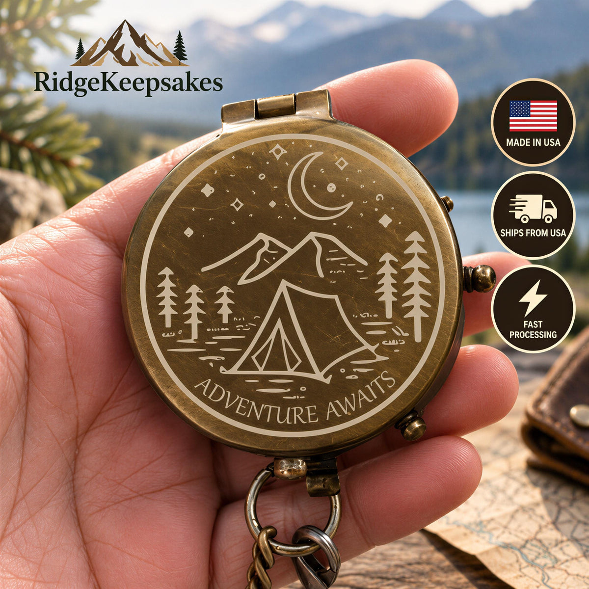 A hand holding a compass with a design of mountains, trees, and a tent, with the text "Adventure Awaits" printed on it.