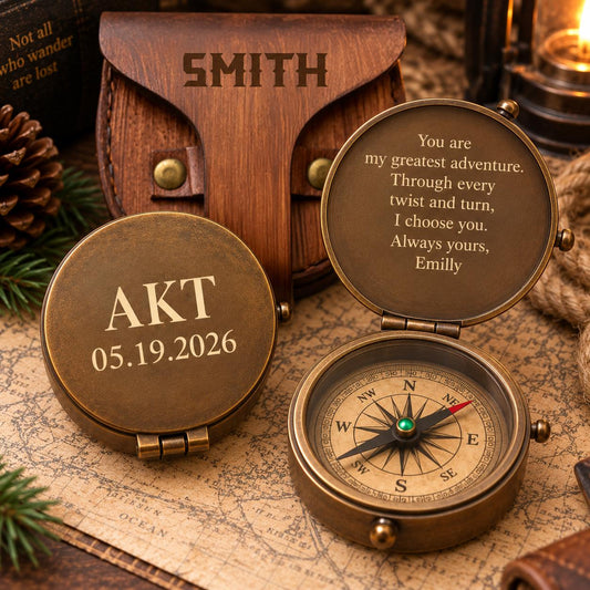 A personalized compass with a message engraved on it, placed on a map and surrounded by pine cones.