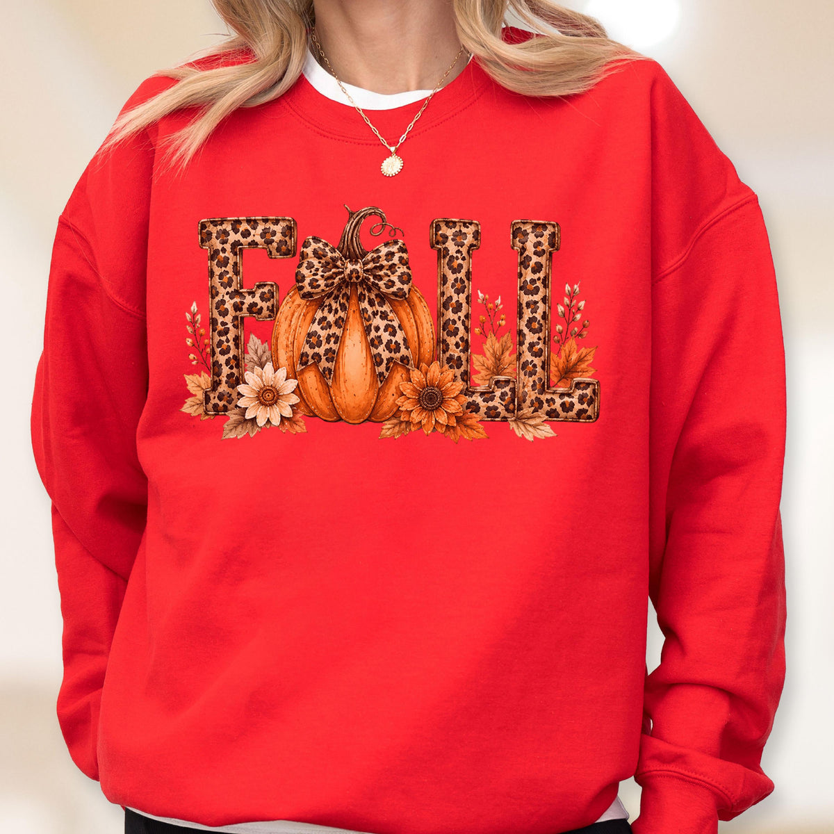 May include: A bright red crewneck sweatshirt featuring a graphic print on the chest. The design displays the word FALL in leopard print lettering, with an orange pumpkin replacing the letter A, adorned with a leopard print bow and sunflowers.