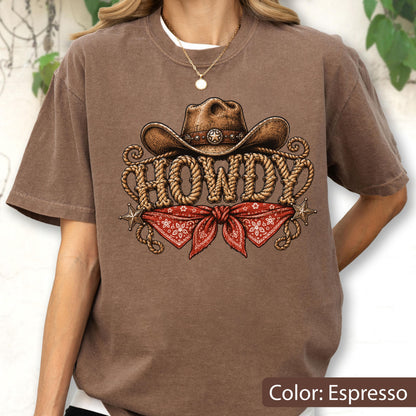 May include: An espresso-colored t-shirt featuring a graphic print of a brown cowboy hat above the word HOWDY written in a rope-style font, with a red patterned bandana tied below and two small star accents on the sides of the design.