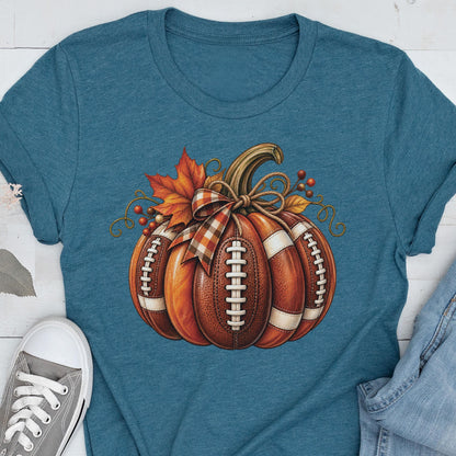 May include: A heathered teal short-sleeve t-shirt featuring a central graphic of a pumpkin designed with the texture and white laces of an American football. The pumpkin is decorated with a plaid ribbon bow, orange maple leaves, and small berries.