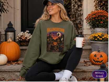 May include: An olive green crewneck sweatshirt featuring a graphic print of a spooky town scene with the text HALLOWEENTOWN and EST 1998. The design includes a large jack-o'-lantern, a flying witch, a black cat, and silhouettes of buildings.