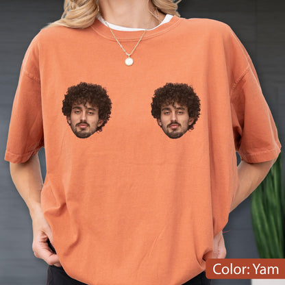 May include: A yam-colored short-sleeve t-shirt featuring two identical photographic prints of a person with dark curly hair and a beard positioned on the chest area. The garment has a crew neckline and a relaxed fit, showcasing a solid orange-toned fabric.