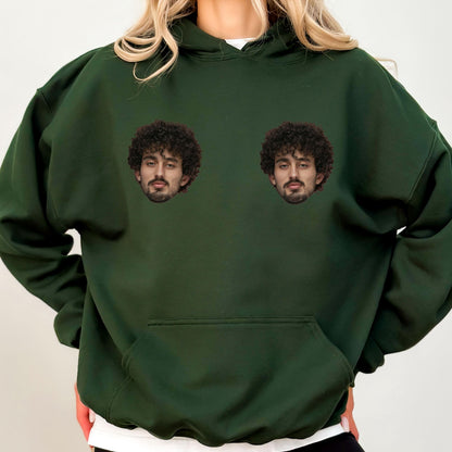 May include: A dark forest green hooded sweatshirt featuring a large front kangaroo pocket and two identical photographic prints of a person with dark curly hair and a beard positioned on the upper chest area of the garment.
