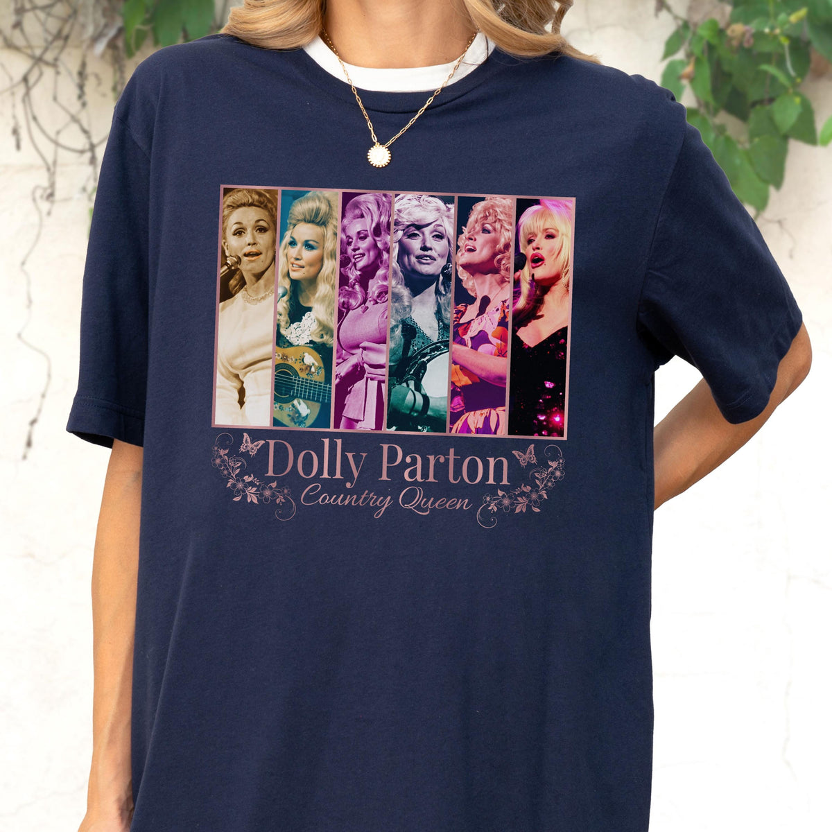 May include: A navy blue short-sleeve t-shirt featuring a graphic print of six vertical panels showing different portraits of Dolly Parton. Below the images, the text reads Dolly Parton Country Queen, surrounded by decorative floral and butterfly line art.