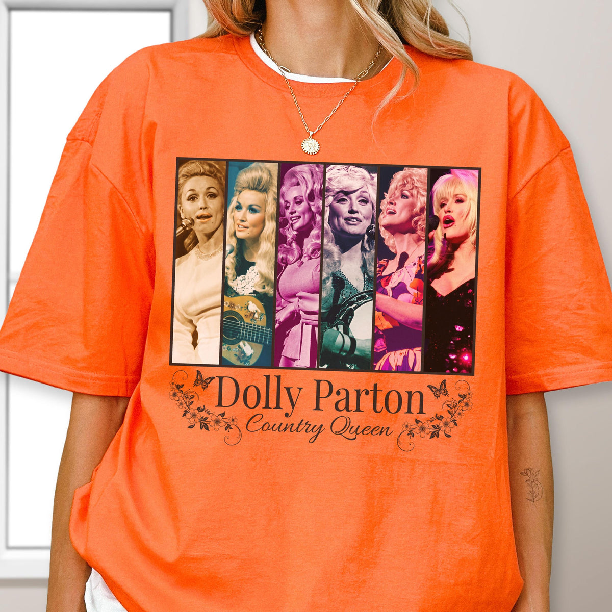 May include: A bright orange t-shirt featuring a rectangular graphic print with six distinct portraits of Dolly Parton in various outfits and poses. Below the images, the text reads Dolly Parton Country Queen, framed by small butterfly and floral illustrations.