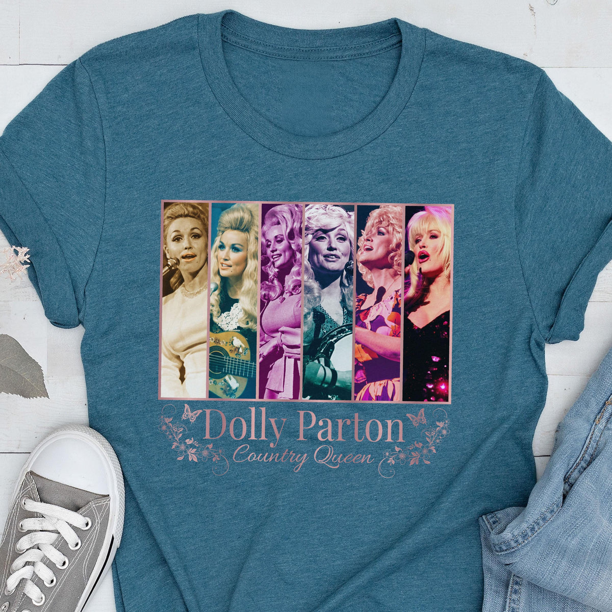 May include: A teal short-sleeved t-shirt featuring a graphic print of six vertical panels showing different portraits of Dolly Parton. Below the images, the text reads "Dolly Parton" and "Country Queen" in a light pink font with butterfly accents.