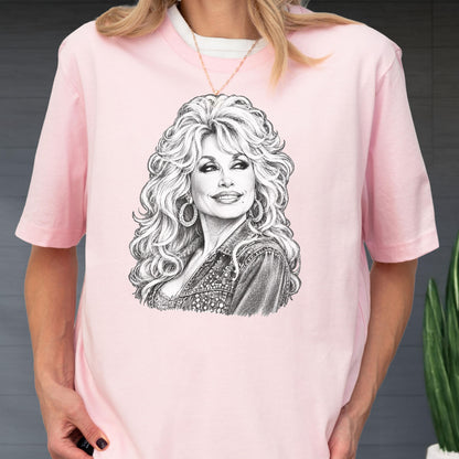 May include: A light pink short-sleeved t-shirt featuring a detailed black and white pencil-style sketch of a person with voluminous blonde hair, hoop earrings, and a denim jacket. The graphic is centered on the chest of the garment.