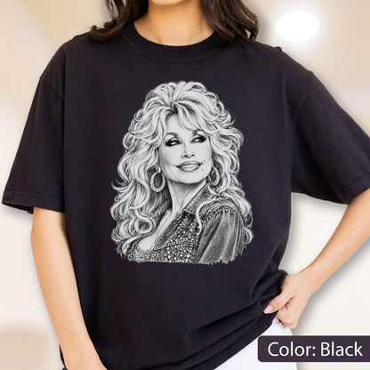 May include: A black short-sleeved t-shirt featuring a detailed white line-art illustration of a person with voluminous wavy hair, wearing large hoop earrings and a textured jacket. The graphic is centered on the chest of the garment.