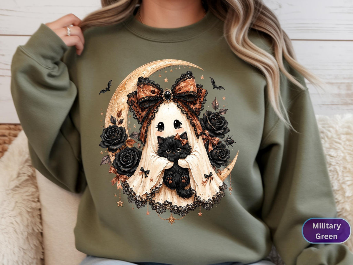 May include: A military green sweatshirt featuring a graphic of a ghost wearing a large leopard print bow, holding a black kitten. The design includes a crescent moon, black roses, small stars, and bats, all rendered in a detailed, illustrative style.