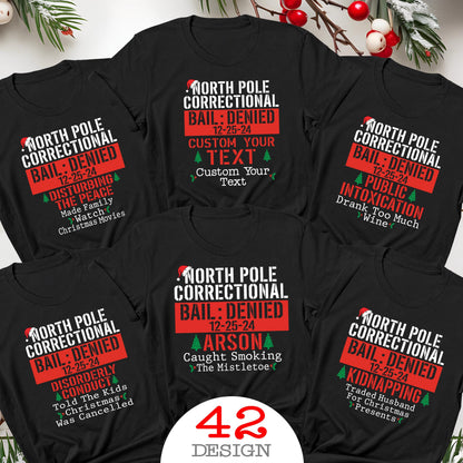 May include: A collection of black t-shirts featuring white and red graphic text that reads North Pole Correctional, Bail: Denied, 12-25-24, and various humorous holiday-themed offenses like Disturbing the Peace, Public Intoxication, Arson, and Kidnapping.