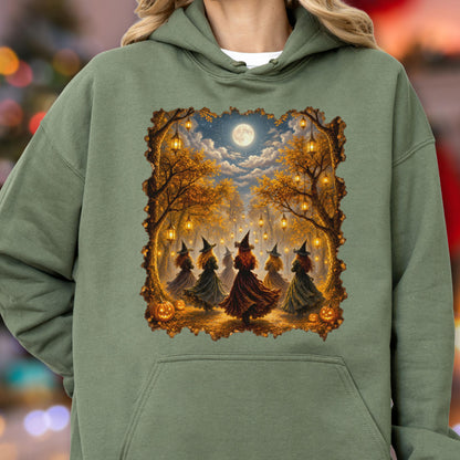 May include: An olive green hooded sweatshirt featuring a rectangular graphic print of five figures wearing pointed hats and long dresses standing in a forest at night. The scene includes hanging lanterns, autumn trees, a full moon, and pumpkins.