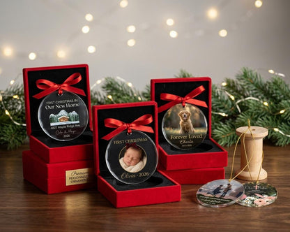 May include: Three circular glass ornaments with red ribbons, each displayed in a red velvet box. One features a house illustration, one a baby photo, and one a dog photo. Two additional ornaments lie flat, one with a couple and one with floral art.