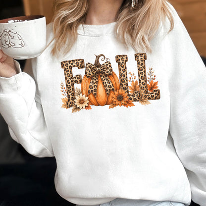 May include: A white crewneck sweatshirt featuring a graphic print of the word FALL in leopard print lettering. The letter A is replaced by an orange pumpkin with a leopard print bow, surrounded by sunflowers and autumn leaves in warm tones.