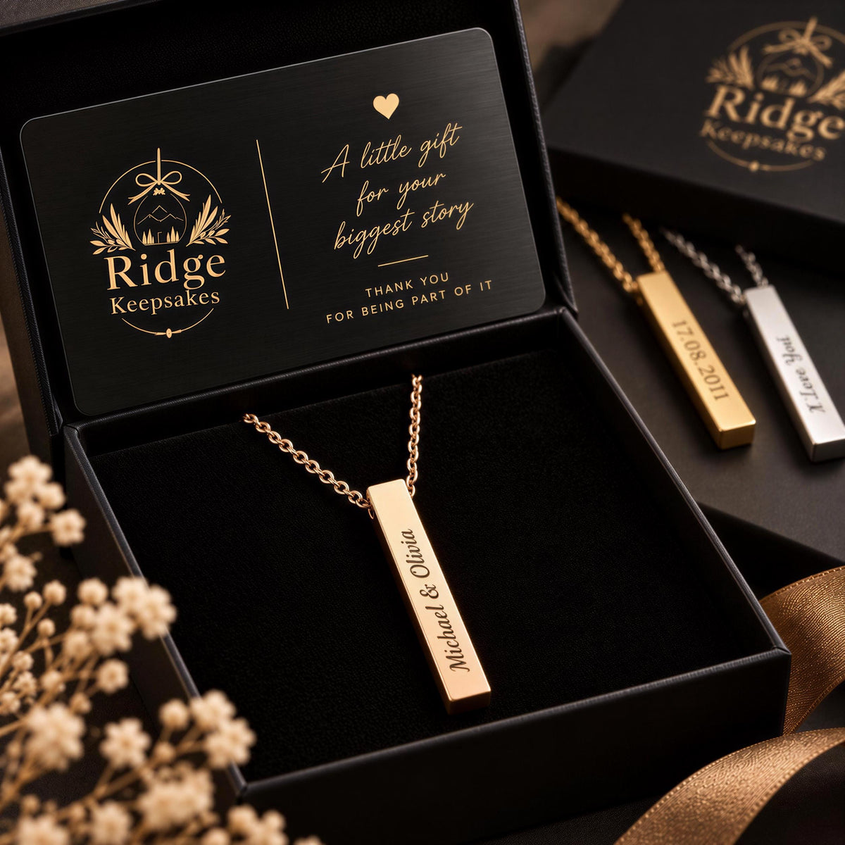 A black jewelry box containing a gold necklace with a personalized pendant, and a card inside the box with a message about the necklace.