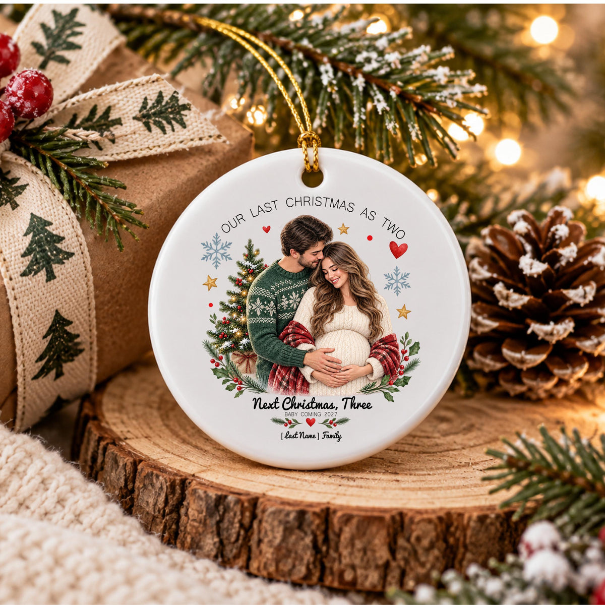 May include: A round white ceramic ornament featuring a printed image of a couple embracing, with the text "OUR LAST CHRISTMAS AS TWO" at the top and "NEXT CHRISTMAS, THREE" at the bottom, accented with holiday graphics and a gold hanging cord.