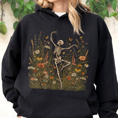 May include: A black hooded sweatshirt featuring a graphic print of a skeleton dancing amidst a field of colorful wildflowers and small butterflies. The design includes various floral shapes in shades of orange, yellow, white, and green.