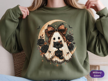 May include: A military green sweatshirt featuring a graphic print of a ghost wearing a large brown bow and holding a black kitten. The design includes a crescent moon, black roses, and small bats, all rendered in a detailed, illustrative style.