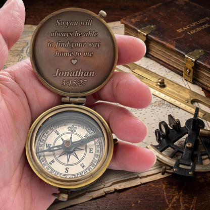 May include: A round brass pocket compass with a hinged lid. The interior lid is engraved with the text: So you will always be able to find your way home to me, a heart symbol, Jonathan, and 3/15/27. The compass face features a needle and cardinal directions.