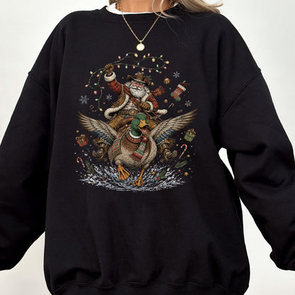 May include: A black crewneck sweatshirt featuring a graphic print of Santa Claus wearing a cowboy hat and vest, riding a flying mallard duck. The design includes colorful Christmas lights, snowflakes, gift boxes, and candy canes in the background.