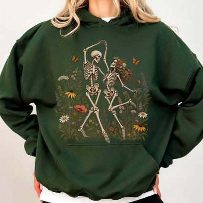 May include: A dark forest green hooded sweatshirt featuring a graphic print of two skeletons dancing in a field of colorful wildflowers and butterflies. The hoodie includes a front kangaroo pocket, long sleeves, and a drawstring hood design.