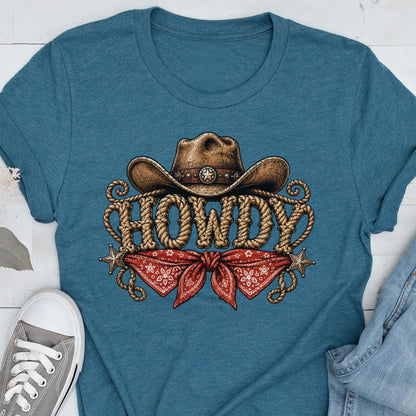 May include: A teal short-sleeved t-shirt featuring a graphic print of a brown cowboy hat above the word HOWDY written in a rope-style font. Below the text is a red bandana with a white pattern, flanked by two small silver-toned stars.