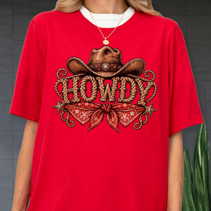 May include: A bright red short-sleeved t-shirt featuring a graphic print of a brown cowboy hat resting above the word HOWDY, which is written in a rope-style font. Below the text is a red bandana with a white floral pattern and two star icons.