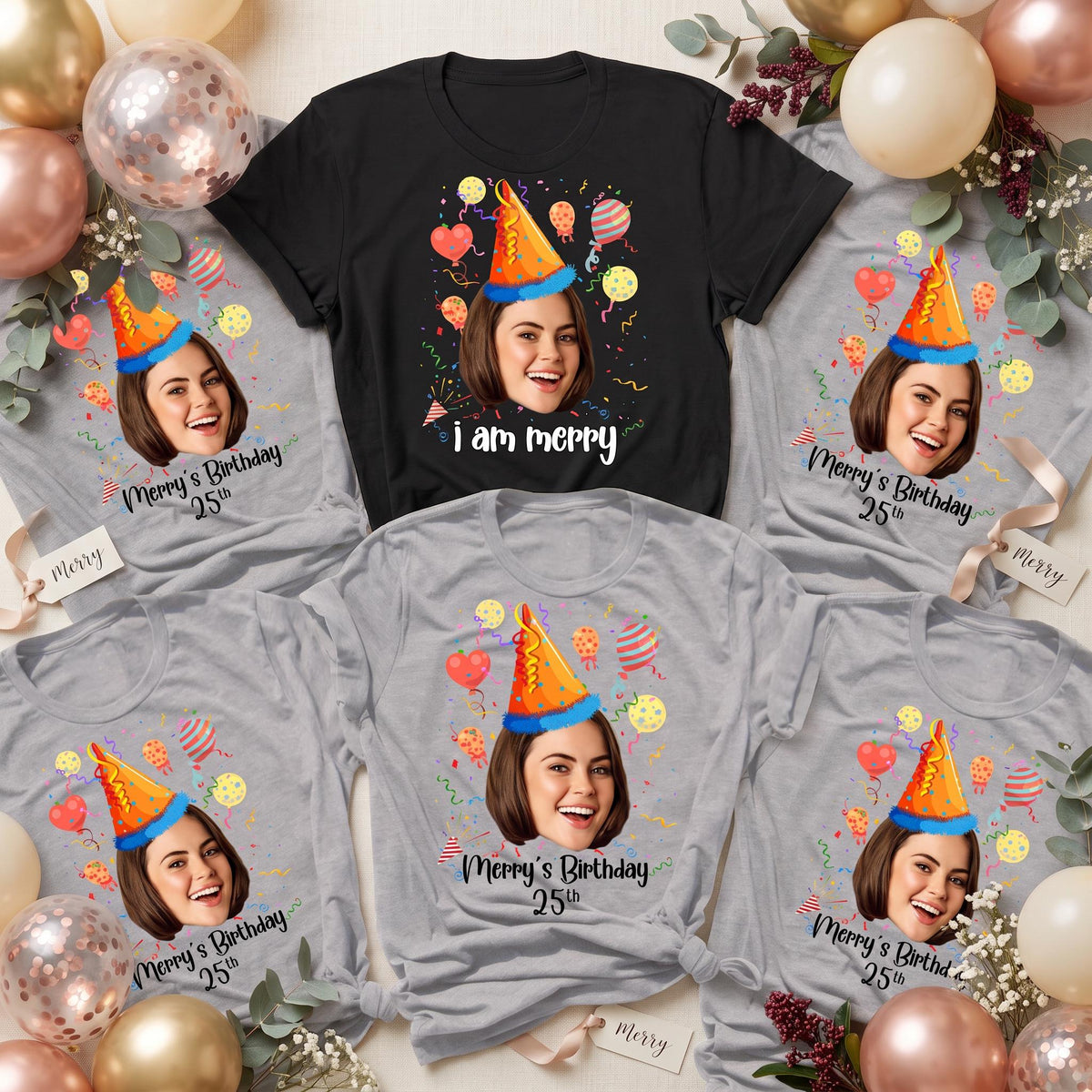 May include: A collection of black and gray t-shirts featuring a custom photo of a person wearing a blue and orange party hat, surrounded by colorful balloons and confetti. The text "Merry's Birthday 25th" or "i am merry" is printed below the face.