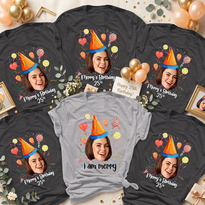 May include: A collection of five t-shirts, four in dark gray and one in light gray, each featuring a printed graphic of a person wearing a blue and orange party hat, surrounded by colorful balloons and confetti, with the text Merry's Birthday 25th.