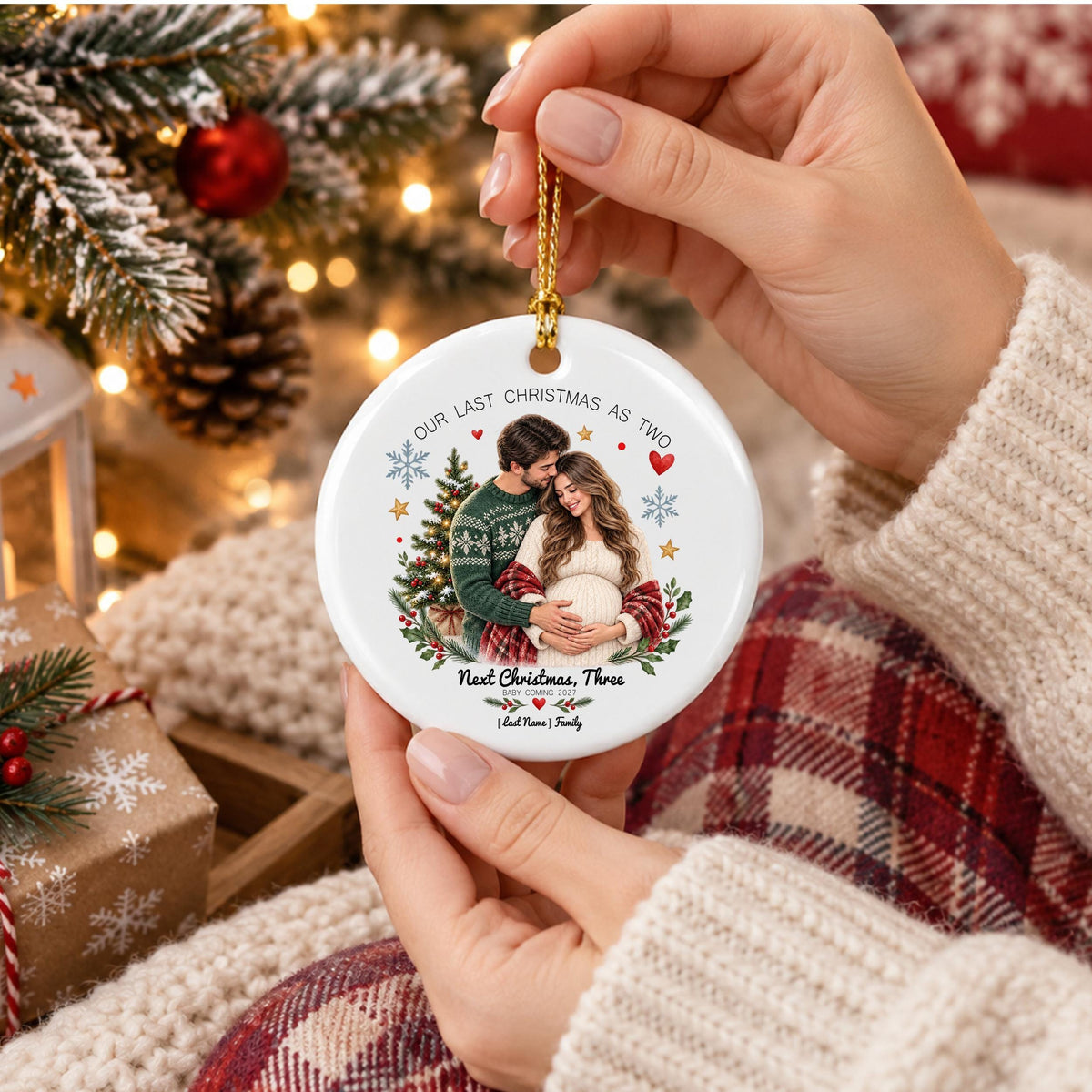 May include: A round white ceramic Christmas ornament featuring a printed image of a couple embracing in front of a Christmas tree. The text reads Our Last Christmas As Two, Next Christmas, Three, Baby Coming 2027, and Last Name Family with hearts.