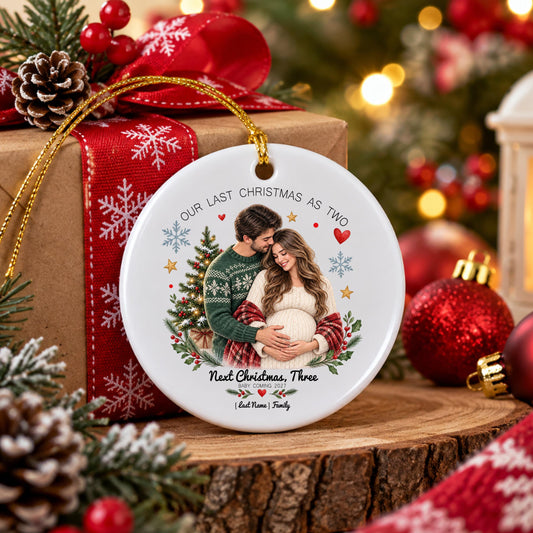 May include: A round white ceramic ornament featuring a printed image of a couple embracing, with the text "OUR LAST CHRISTMAS AS TWO" at the top and "Next Christmas, Three" at the bottom, accented by a Christmas tree, snowflakes, and hearts.
