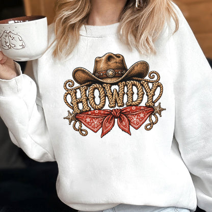 May include: A white crewneck sweatshirt featuring a graphic print of a brown cowboy hat above the word HOWDY written in a rope-style font. Below the text is a red bandana with a white floral pattern, flanked by two small metallic stars.