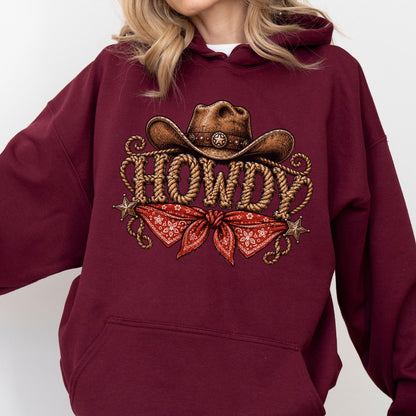 May include: A maroon hooded sweatshirt featuring a graphic print of a brown cowboy hat, the word HOWDY written in a rope-style font, a red bandana with a white floral pattern, and two small metallic-colored stars on the sides of the design.