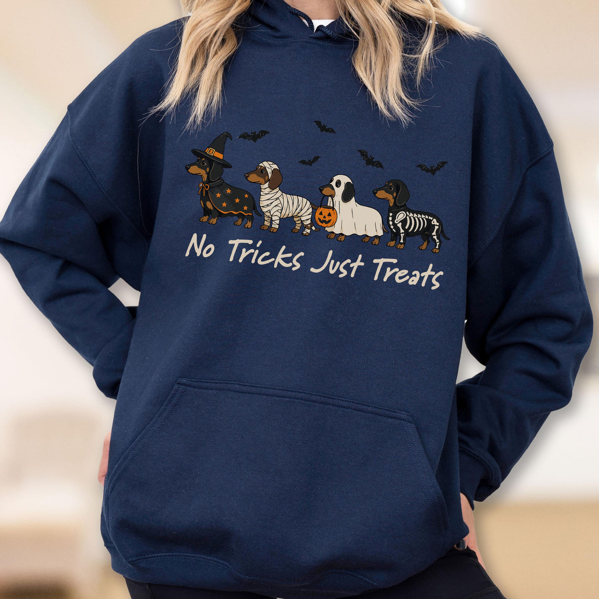 May include: A navy blue hooded sweatshirt featuring a graphic of four dachshunds in Halloween costumes, including a witch, a mummy, a ghost holding a pumpkin bucket, and a skeleton. The text "No Tricks Just Treats" is printed below the dogs.