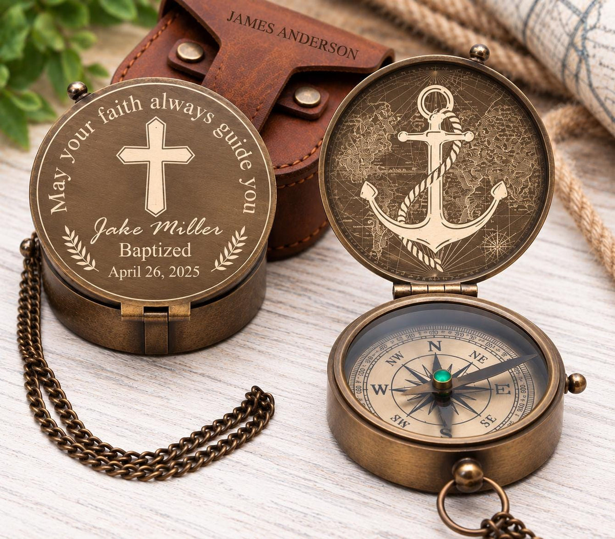 Brass pocket compass with Christian engraving examples, including a cross with personalized text and a large anchor design, displayed with a brown leather pouch.