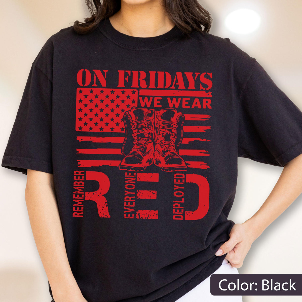 May include: A black t-shirt featuring a red graphic of an American flag with a pair of combat boots in the center. The text reads ON FRIDAYS WE WEAR RED and REMEMBER EVERYONE DEPLOYED in a distressed, bold, block-style red font.