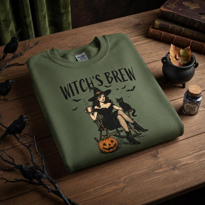 May include: An olive green crewneck sweatshirt featuring a graphic print of a witch in a black dress and hat sitting in a rocking chair with a black cat, a pumpkin, and bats. The text WITCH'S BREW is printed in black above the illustration.