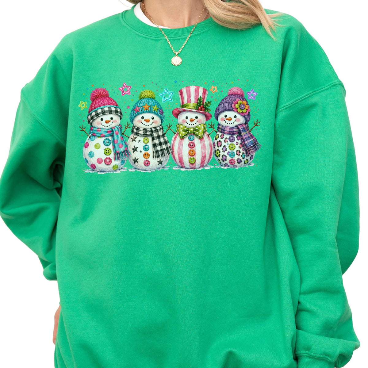 May include: A bright green crewneck sweatshirt featuring a graphic print of four snowmen wearing colorful hats and scarves. The snowmen are decorated with various patterns including buttons, stars, and flowers, accented by small colorful stars above them.