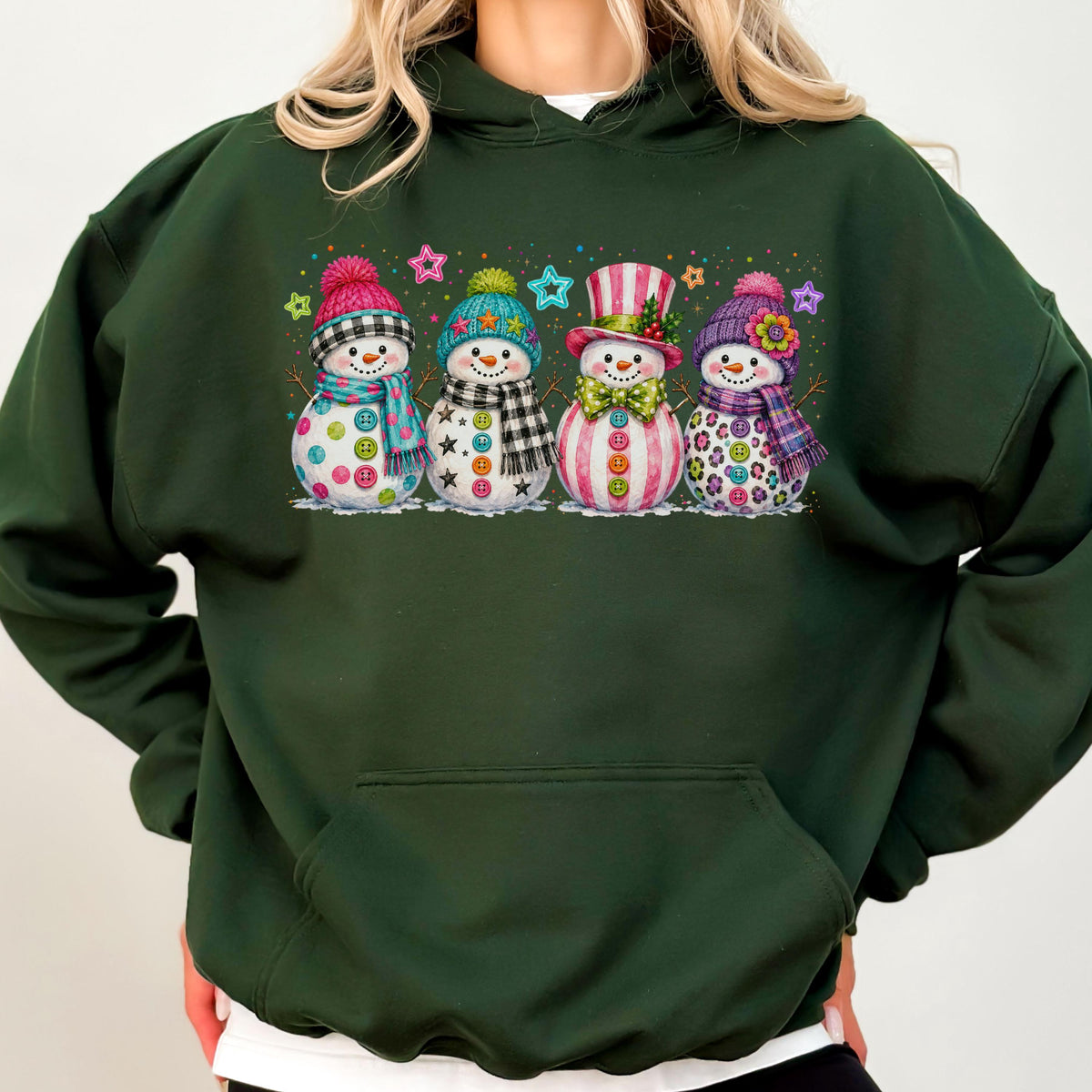 May include: A dark forest green hooded sweatshirt featuring a graphic print of four snowmen. Each snowman wears a unique hat and scarf, decorated with colorful buttons and surrounded by small, multi-colored star shapes across the chest area.