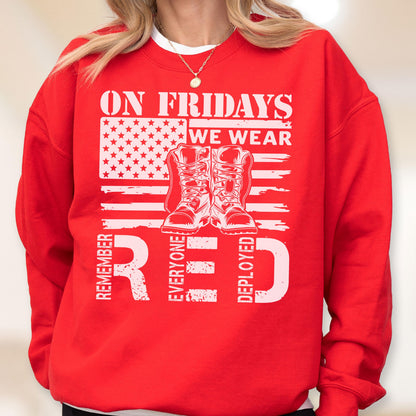 May include: A bright red crewneck sweatshirt featuring a white graphic print. The design includes the text ON FRIDAYS WE WEAR, a stylized American flag, a pair of military boots, and the text REMEMBER EVERYONE DEPLOYED in large white lettering.